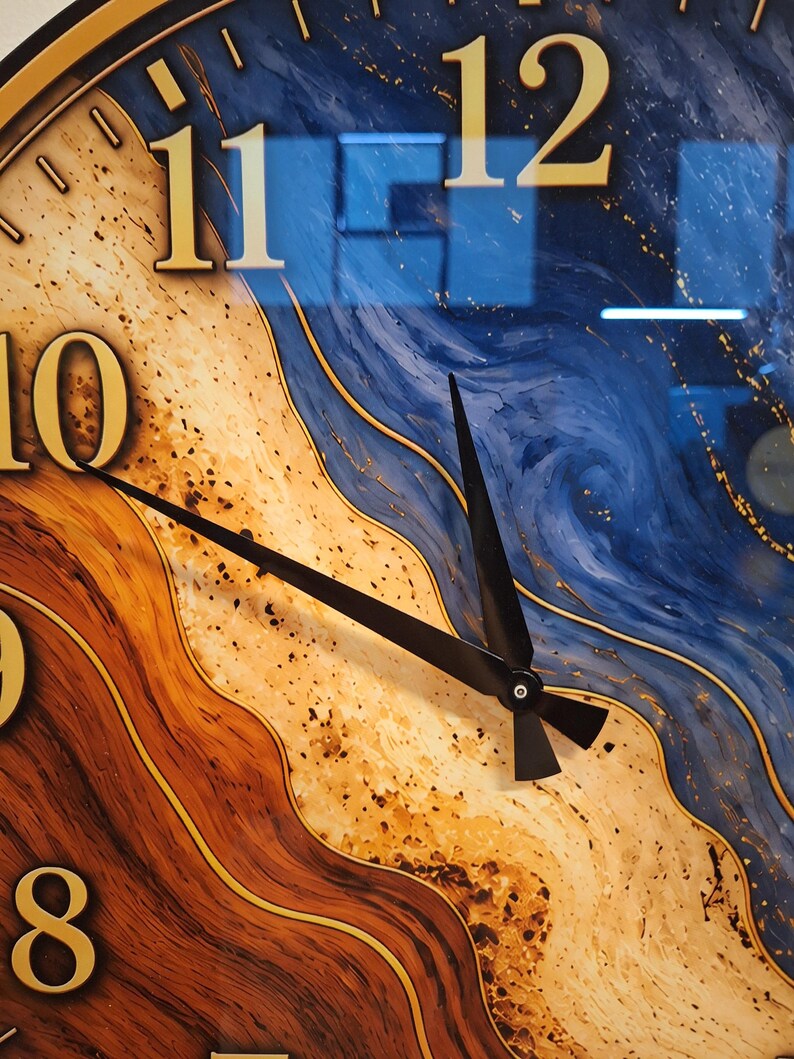 May include: A wall clock face featuring a swirling abstract pattern of deep blue, sandy beige, and dark brown tones. The clock has large gold-colored numerals for 8, 10, 11, and 12, with two thin black hands pointing toward the center.