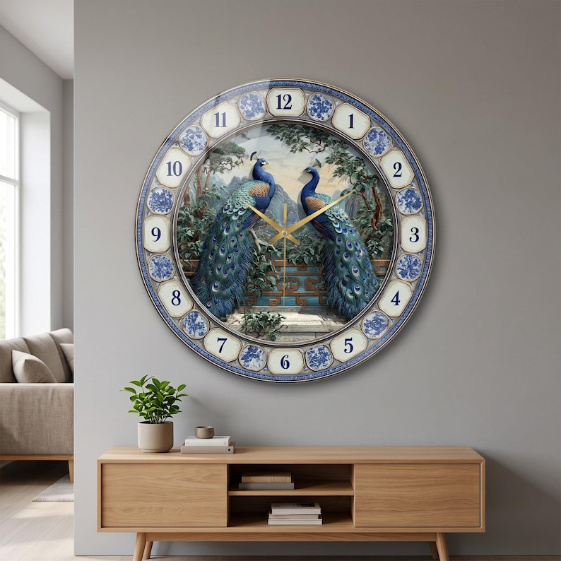 May include: A round wall clock featuring a central illustration of two peacocks perched on a stone ledge amidst trees. The clock face has a blue and white patterned border with black numerals from 1 to 12 and thin gold-colored clock hands.