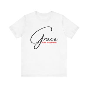 Può includere: Una tazza di ceramica bianca con manico nero e la scritta "But First, Coffee" in grassetto nero. La tazza è appoggiata su una superficie di legno. La tazza è alta circa 10 cm.