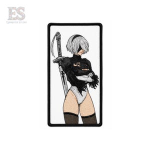 May include: Embroidered patch featuring a stylized anime character with short white hair, a black outfit, and a sword. The character is set against a white background with a black border. The patch has the "ES EMBROFILE STUDIO" logo.