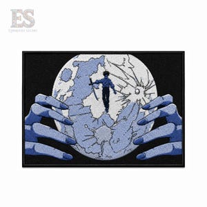 May include: A rectangular embroidered patch featuring a large, pale blue moon with a cracked surface. A small figure in a dark blue outfit stands on the moon holding a sword. Two large, blue, claw-like hands frame the moon against a black background.