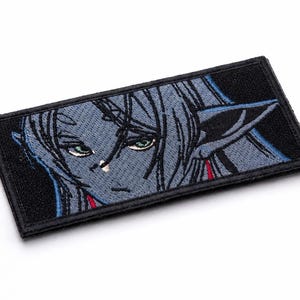 May include: Embroidered patch featuring a stylized anime character with blue skin, long hair, and pointed ears. The patch has a black border and a detailed design with green eyes and red accents. Ideal for jackets, bags, or cosplay.
