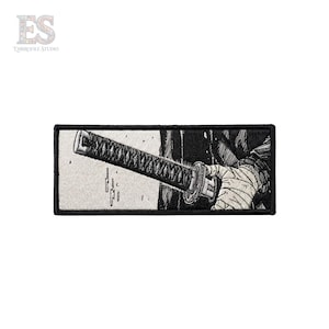 Könnte beinhalten: Gestickter Aufnäher mit einer Schwarz-Weiß-Illustration eines Katana-Schwertes. Der Griff des Schwertes ist umwickelt, und die Klinge ist teilweise sichtbar. Der Aufnäher hat einen schwarzen Rand und eine rechteckige Form.