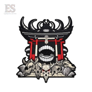Peut inclure: Un écusson brodé représentant une structure de portail torii noir et rouge avec une grande bouche ouverte montrant des dents au centre. Le motif comprend trois crânes d'animaux à la base, réalisés avec des fils gris, blancs et noirs.