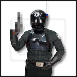May include: Black Star Wars TIE Fighter Pilot costume. The costume includes a glossy black helmet with a white Imperial symbol, a black chest plate, and a black jumpsuit. The pilot is wearing black gloves and a utility belt.