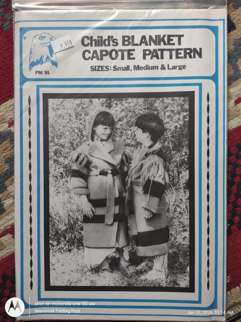 K&ouml;nnte beinhalten: Eine Schnittmusterh&uuml;lle mit dem Titel Child's BLANKET CAPOTE PATTERN f&uuml;r die Gr&ouml;&szlig;en Small, Medium & Large. Die wei&szlig;e Verpackung hat einen blauen Rand und ein schwarz-wei&szlig;es Foto von zwei Kindern, die kapuzenbesetzte, geg&uuml;rtete M&auml;ntel tragen.