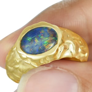 May include: A gold ring with a large, round, blue opal gemstone set in a textured gold band.
