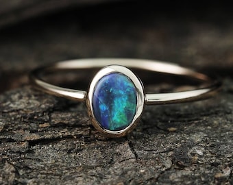 May include: A delicate gold ring with a bezel setting featuring a vibrant blue-green opal.
