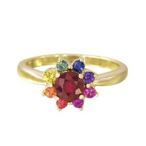 Peut inclure: Une bague en or avec une grande pierre précieuse en rubis rouge entourée de pierres précieuses plus petites dans un arc-en-ciel de couleurs.