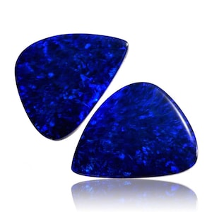 Op de afbeelding: Twee blauwe gitaarplectrums gemaakt van iriserend materiaal. De plectrums zijn driehoekig met afgeronde randen.