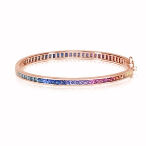 May include: A rose gold bangle bracelet with a rainbow of square-shaped gemstones set in a continuous line around the band.