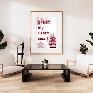 May include: A framed print with the words "Dream big Start small" in red text, accompanied by illustrations of Japanese pagodas and cherry blossoms. The print hangs above a black coffee table and two white armchairs.