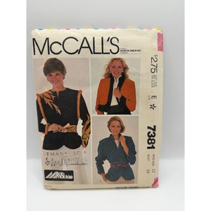 Puede incluir: Un sobre de patrón de costura vintage McCall's 7381 con diseños de Bob Mackie. La portada muestra tres variaciones de chaqueta: una negra con bordado dorado, una naranja con ribete negro y una de color verde azulado con un cinturón.