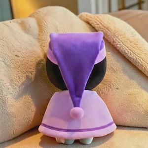 May include: A white ceramic mug with a black handle and the text "But First, Coffee" in a bold, black font. The mug is set against a blurred background, suggesting a cozy setting. The mug appears to be approximately 4 inches tall.