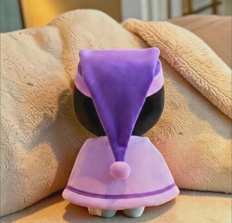 May include: A white ceramic mug with a black handle and the text "But First, Coffee" in a bold, black font. The mug is set against a blurred background, suggesting a cozy setting. The mug appears to be approximately 4 inches tall.