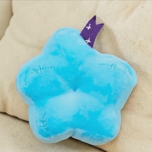 May include: A white ceramic mug with a black handle and the text "But First, Coffee" in a bold, black font. The mug is set against a blurred background, suggesting a cozy setting.