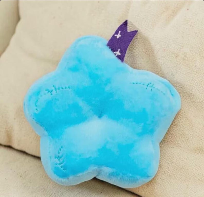 May include: A white ceramic mug with a black handle and the text "But First, Coffee" in a bold, black font. The mug is set against a blurred background, suggesting a cozy setting.