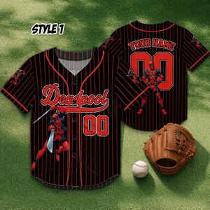 May include: Black baseball jersey with red pinstripes, featuring the word "Deadpool" and the number "00" in red. The jersey has a Deadpool graphic and the text "YOUR NAME" on the back. A baseball glove and ball are also in the image.
