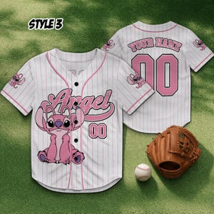 May include: White baseball jersey with pink pinstripes, featuring a pink cartoon character and the word "Angel". The jersey has the number "00" and a baseball glove and ball are next to it.