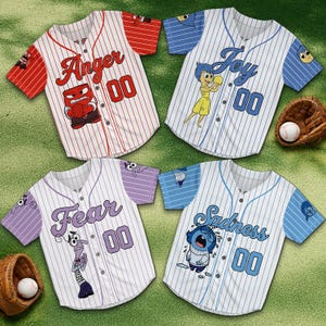 Könnte beinhalten: Vier Baseball-Trikots mit Charakterdesigns aus dem Film Alles steht Kopf. Jedes Trikot zeigt eine andere Emotion: Wut, Freude, Angst und Traurigkeit. Die Trikots sind weiß mit vertikalen Nadelstreifen und der Nummer "00".