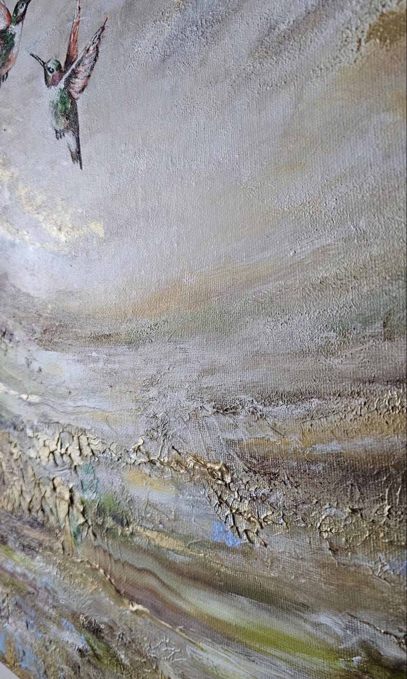 May include: A textured oil painting on canvas featuring two hummingbirds in flight against a neutral background. The artwork displays thick, layered brushstrokes in shades of beige, cream, and gold, with subtle hints of green and blue throughout.