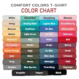 May include: A colour chart for Comfort Colours T-shirts, displaying a variety of hues. The chart shows folded t-shirts in shades like white, ivory, banana, and mustard, alongside others such as terracotta, burnt orange, and grey. The text "COLOUR CHART" is at the top.