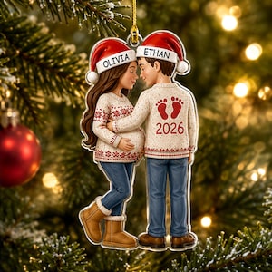 Può includere: Un addobbo natalizio in acrilico trasparente con l'illustrazione di una persona incinta e del partner che indossano maglioni color crema abbinati, jeans blu e cappelli da Babbo Natale rossi con i nomi Olivia ed Ethan stampati sui bordi.