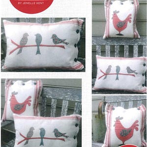 May include: Off-white rectangular and square cushions featuring red and blue bird or rooster appliqués. The rectangular cushions show three birds on a branch, while the square cushions feature a single rooster. Each cushion has red striped edges and black buttons.