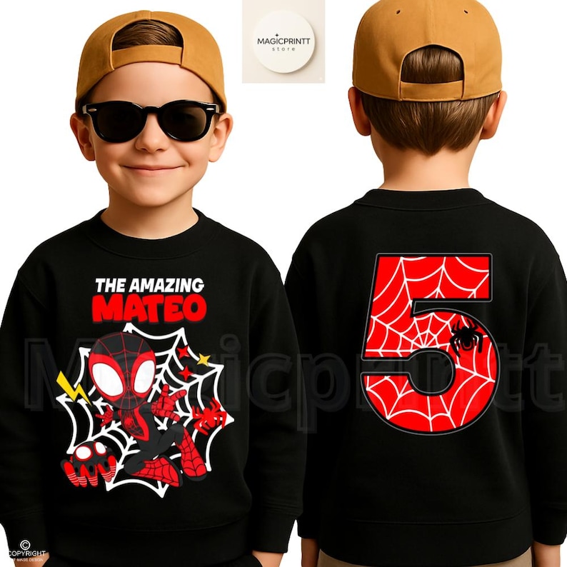 May include: Black sweatshirt featuring a cartoon superhero design with the text "THE AMAZING MATEO". The back of the sweatshirt displays a large number "5" with a spiderweb design and a spider. The sweatshirt is worn by a child.