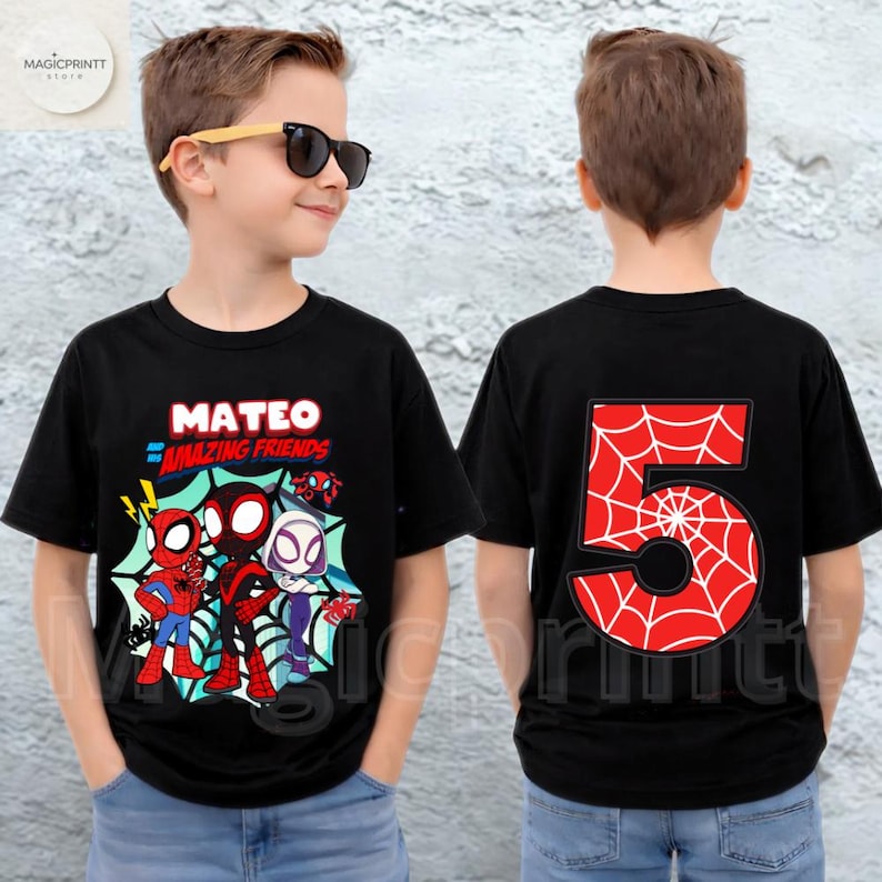 Puede incluir: Camiseta negra con personajes de Spider-Man, el nombre "MATEO" y "AMAZING FRIENDS" en rojo y azul. La parte trasera muestra un gran n&uacute;mero rojo "5" con un dise&ntilde;o de telara&ntilde;a blanca. La camiseta la lleva un ni&ntilde;o.