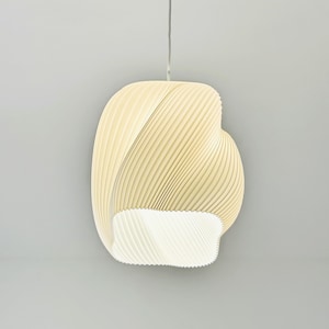 May include: A cream-coloured, modern pendant light fitting. The light has a unique, swirling design with a pleated texture. The bottom of the light is open, revealing a bright white interior. The light hangs from a thin, white cord.