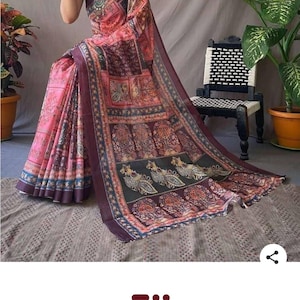 May include: A pink and black printed cotton saree with a decorative border and peacock design. The saree has a floral and geometric pattern. The text at the bottom of the image says "black printed pure cotton black saree with blouse."