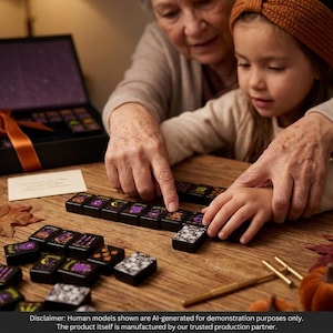 May include: A set of black mahjong tiles featuring colorful Halloween-themed illustrations including pumpkins, skulls, and purple accents. The tiles are arranged on a wooden surface alongside a black storage box with an orange ribbon.