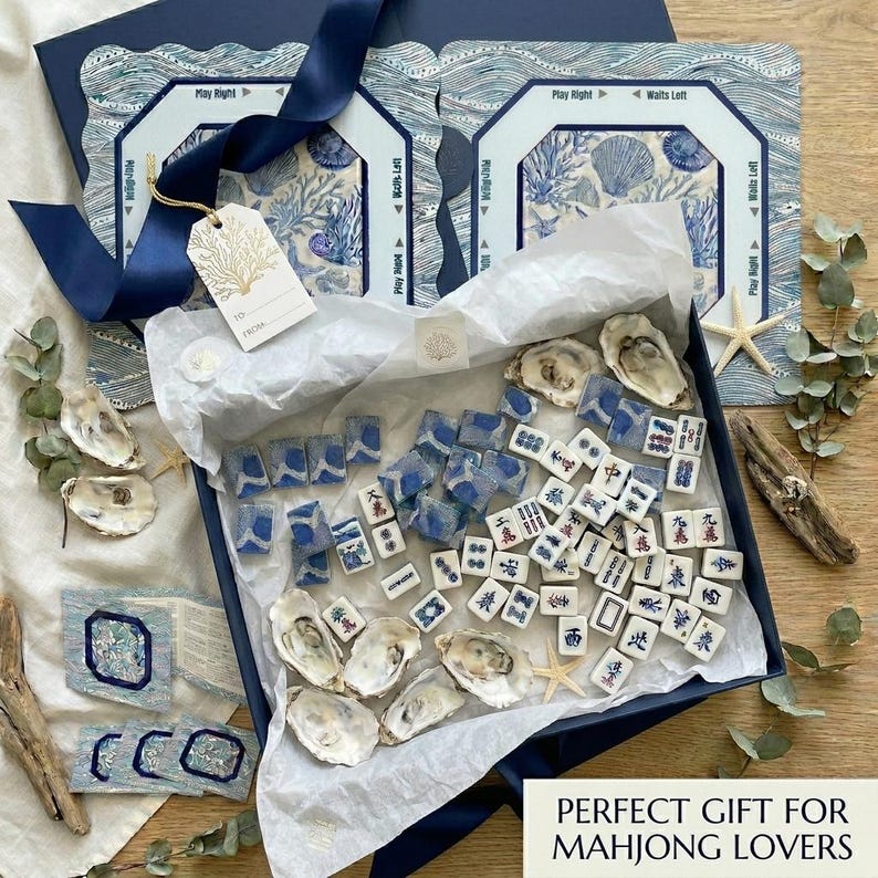 Complete 4-piece American mahjong gift set in blue and white ocean print — includes choice of square or scalloped mahjong mat with rules, custom-back mahjong tiles, acrylic card holders, and a zippered tile bag in coordinating coral and shell design. A stunning mahjong gift for 50th or 80th birthdays.
