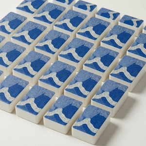 American mahjong tiles with custom blue and white coral print backs, face-up on a linen surface — part of a fully coordinated coastal mahjong accessories set. A unique mah jongg tile set and meaningful grandma gift from grandkids who want to give something truly special.