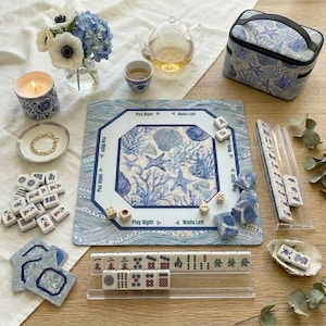 Complete 4-piece American mahjong gift set in blue and white ocean print — includes choice of square or scalloped mahjong mat with rules, custom-back mahjong tiles, acrylic card holders, and a zippered tile bag in coordinating coral and shell design. A stunning mahjong gift for 50th or 80th birthdays.