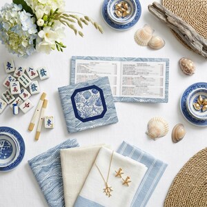Acrylic mahjong card holder with line finder alongside a blue and white shell-print mahjong card sleeve — a mahjong card cover designed for NMJL American mahjong cards. Part of the fully coordinated blue and white coastal mahjong gift bundle.