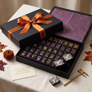 Gothic skull mahjong tiles displayed on a black tablecloth with candles and dark florals for a moody Halloween game night setup.