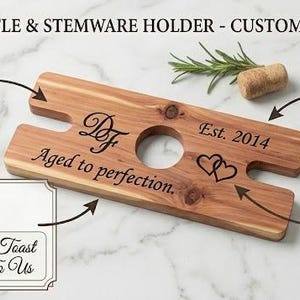 May include: A rectangular wooden bottle and stemware holder featuring a central circular cutout and two side notches. The wood is laser-engraved with the text 'Df', 'Aged to perfection.', 'Est. 2014', and two interlocking heart outlines.
