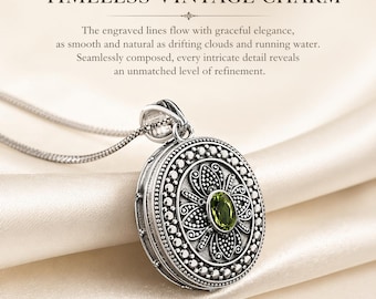 Pode incluir: Um colar com pingente prateado com um charme redondo e ornamentado. O charme apresenta uma pedra preciosa verde central e padrões florais e de pontos detalhados. O texto "TIMELESS VINTAGE CHARM" está no topo.