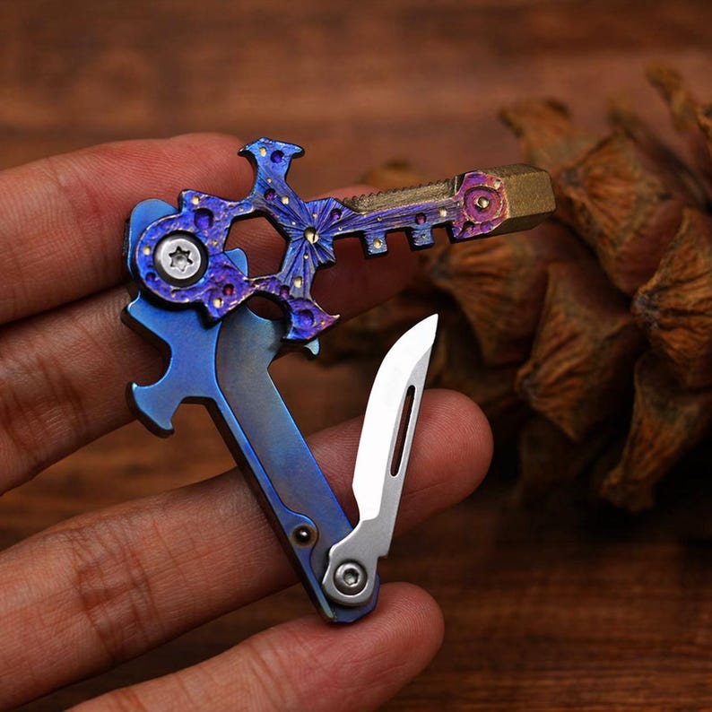 May include: A multi-tool with a blue and purple finish, featuring a key-shaped design with a bottle opener, knife, and other tools. The tool has a metallic finish with gold accents and a small silver blade.