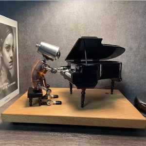 May include: A detailed model of a robot playing a miniature black grand piano. The robot has a silver head and a copper-toned body. The piano is on a wooden base, with a book visible.