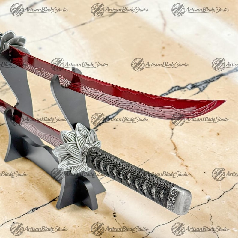 May include: A katana sword featuring a deep red blade with a wavy hamon pattern, a silver lotus-shaped tsuba, and a black cord-wrapped handle. The sword is displayed on a black two-tier stand, showcasing the curved blade and detailed hilt.