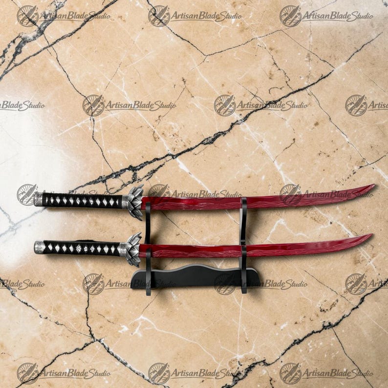 May include: Two swords with curved, deep red blades featuring a subtle wave pattern. The handles are black with a diamond-shaped wrap pattern and silver-toned metal accents at the pommel and guard. The swords rest on a black display stand.