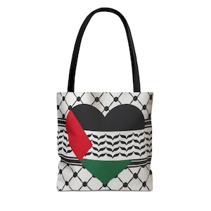 Könnte beinhalten: Eine weiße Tragetasche mit schwarzem Griff. Die Tasche zeigt ein Herzdesign in den Farben der palästinensischen Flagge. Das Herz ist schwarz, mit einem roten Dreieck auf der linken Seite und einem grünen Dreieck unten. Der Hintergrund hat ein schwarz-weißes Muster.