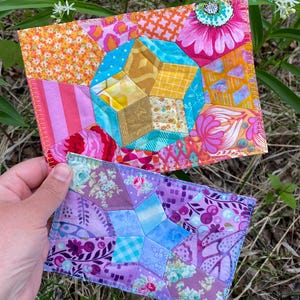 May include: Two colourful patchwork fabric pieces with star designs. The top piece has orange, pink, and yellow hues, while the bottom piece is purple and blue. The text "ATTENTION: PDF Pattern ONLY!" is visible on the top piece.