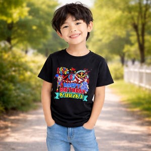 May include: A black t-shirt with a colorful graphic featuring the text "DIGITAL CIRCUS" and "HAPPY BIRTHDAY KANEZKA". The graphic includes circus-themed characters and the number "6". The shirt is worn by a smiling child.