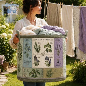 May include: A large, cylindrical, quilted fabric laundry basket featuring a botanical print titled Practical Magic. The design displays illustrations of herbs like rosemary, verbena, and lavender with labels. It is filled with folded linens.