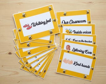 Può includere: Un gruppo di carte gialle e bianche con illustrazioni di api e testo. Le carte presentano frasi come "Walking feet", "Our Classroom" e "Kind hands". Le carte hanno un bordo giallo e sono progettate per scopi educativi.