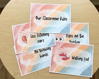 Può includere: Un insieme di schede delle regole della classe con uno sfondo ad acquerello dai colori pastello. Ogni scheda presenta una regola: "Le nostre regole della classe", "Usa le orecchie che ascoltano", "Niente mani che lanciano", "Occhi sull'insegnante" e "Piedi che camminano".